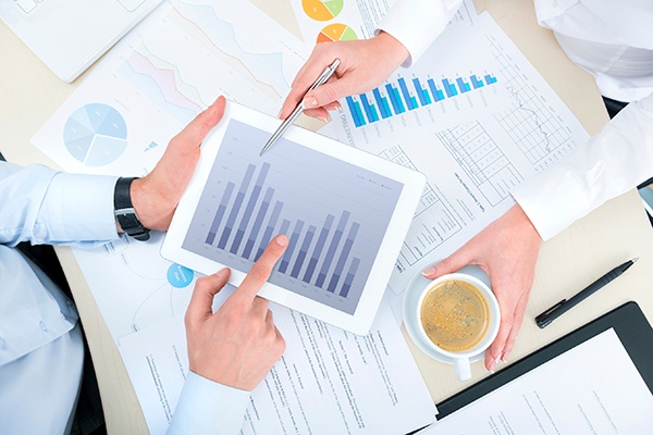 Business people discussing and analyzing market data information on a modern digital tablet computer. Top view photoshoot.